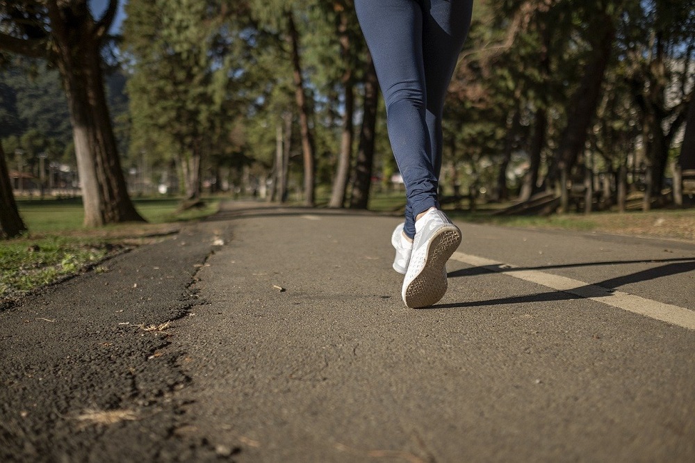 close up of women jogging during morning time on road wearing white shoes