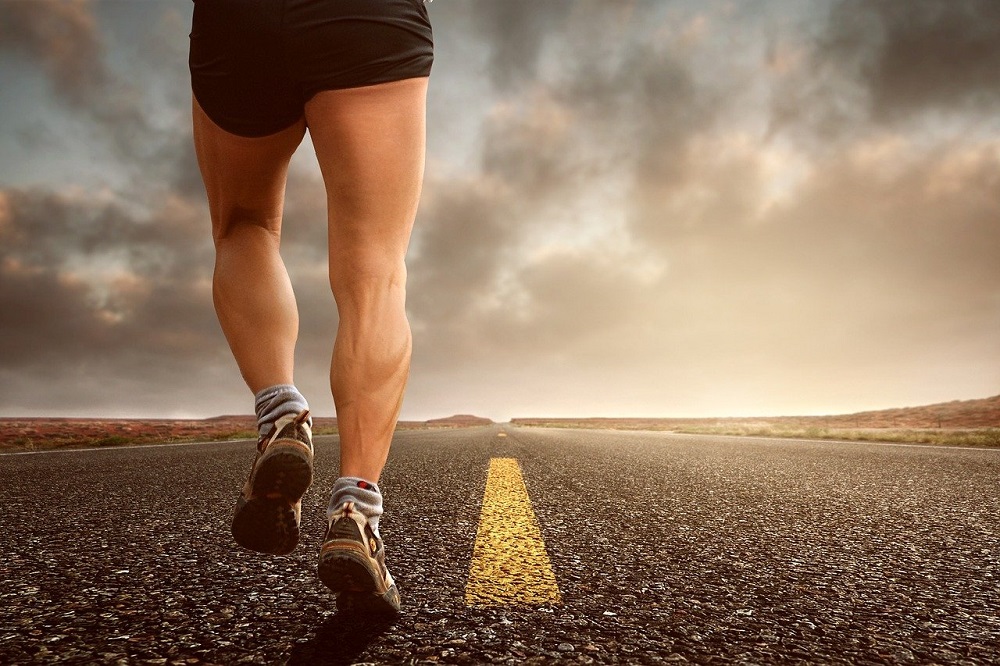 close up of young man doing jogging during morning time on road