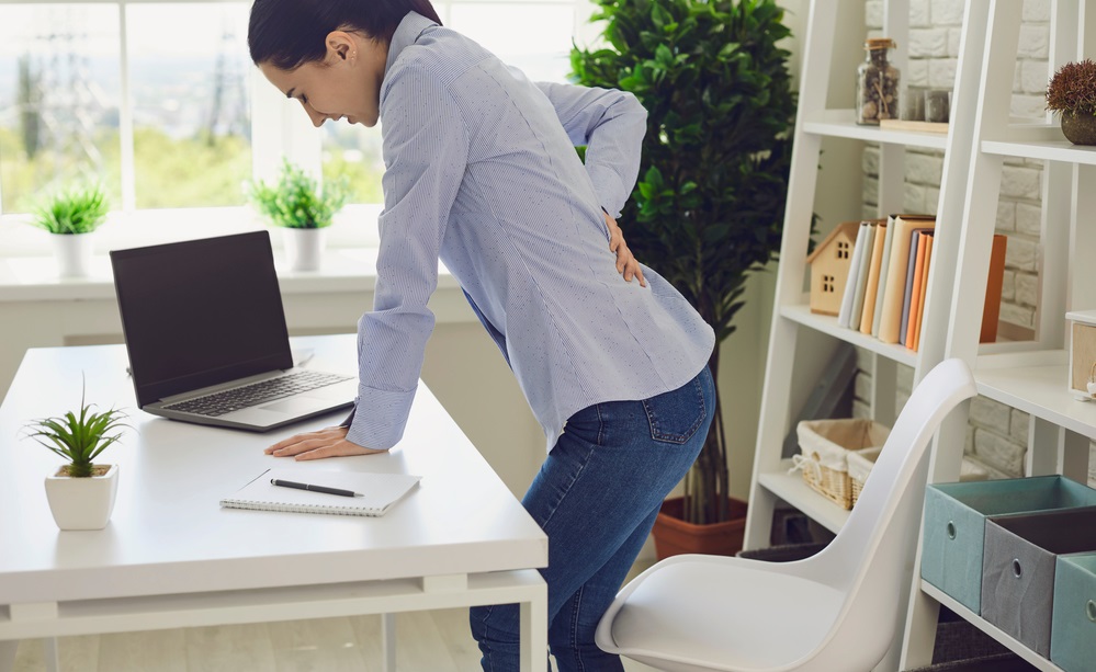 woman suffering from back pain at workplace